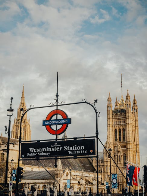 A street-level view of Westminster Station near Victoria Station in London, showing the entrance to the underground subway with a large sign displaying the station name and underground logo. The entra